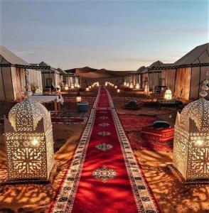 梅尔祖卡Sahara Luxury Tented Camp的一间铺有红地毯的客房和一排帐篷