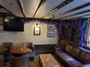 LitherlandJubilee pub的酒吧配有皮沙发、桌子和电视