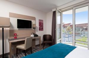 慕尼黑慕尼黑市奥林匹克公园莱昂纳多酒店的酒店客房配有书桌和床。