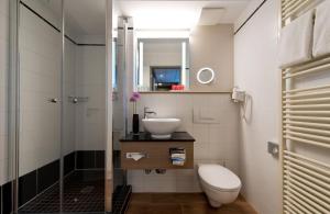 慕尼黑慕尼黑市奥林匹克公园莱昂纳多酒店的浴室配有卫生间、盥洗盆和淋浴。