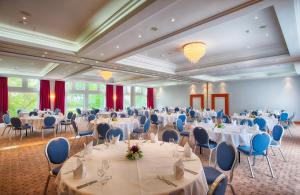 海德堡海德堡莱昂纳多酒店的宴会厅配有白色的桌子和蓝色的椅子