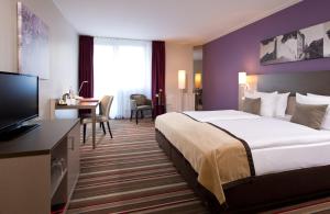 汉诺威汉诺威机场莱昂纳多酒店的酒店客房设有一张大床和一张书桌。