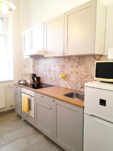 赛特古特哈德D16 Apartman的厨房配有白色橱柜和水槽