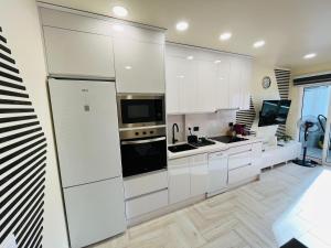 英格兰海滩Atlantic Coast Apartment - Playa Del Inglés的厨房配有白色橱柜和大冰箱。
