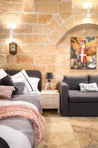 瓦莱塔MCC Suites Valletta的一间卧室配有床、沙发和砖墙