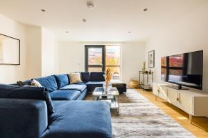 伦敦The Clapham Dream - Captivating 3BDR with Garden & Parking的客厅配有蓝色的沙发和电视