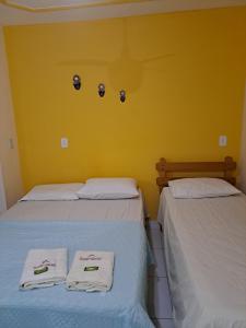 古里里Pousada Maresias Guriri的黄色客房的两张床,配有毛巾