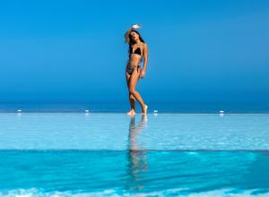 普拉坦斯Atermono Boutique Resort & Spa的一位在海滩上水中行走的女人