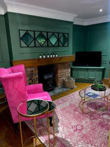 阿伯丁Historic Cottage in the Heart of Old Aberdeen.的客厅配有粉红色的椅子和壁炉
