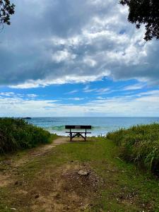 科夫斯港Beachfront Retreat - Ducted Air - Free Wifi的坐在海边泥土路上的长凳