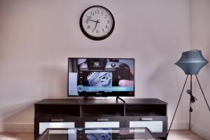 伯明翰Stylish Birmingham City Centre Apartment的客厅配有电视和墙上的时钟