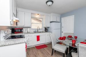 查尔斯顿Adorable Blue Little House的厨房配有白色橱柜和桌椅