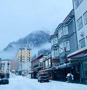 朱诺阿拉斯加酒店及酒吧的一条有建筑物和山的雪覆盖的街道
