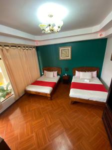 UpalaHotel Wilson Upala的配有绿色墙壁和木地板的客房内的两张床