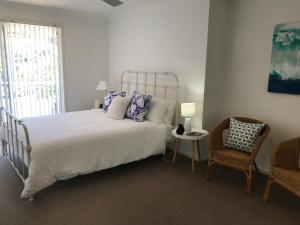 科夫斯港Beachfront Retreat - Ducted Air - Free Wifi的卧室配有床、椅子和窗户。