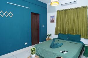 科泽科德Atmos Inn的一间拥有蓝色墙壁的卧室和一张带绿帘的床