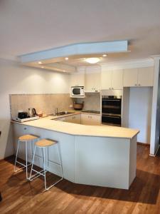 黄金海岸Bayview Bay Apartments and Marina的厨房配有白色橱柜和带凳子的台面