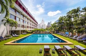 曼谷曼谷大使酒店的一座带躺椅的游泳池和一座建筑