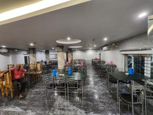BalasoreHotel Narendra Plaza的一间设有桌椅的餐厅,一个男人坐在房间里