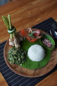 希德门Ume Dukuh Home Sidemen的餐桌上放着一盘饭和蔬菜的食物