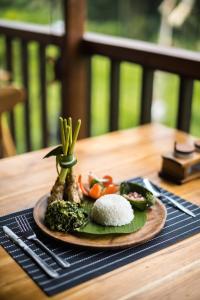 希德门Ume Dukuh Home Sidemen的餐桌上放着一盘饭和蔬菜的食物