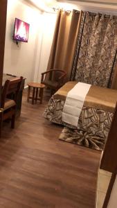 KakamegaHellenis Guest House的一间卧室配有一张带窗帘和桌子的床