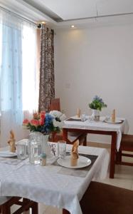 KakamegaHellenis Guest House的一间用餐室,配有2张带白色桌布的桌子