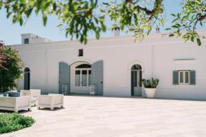 萨维勒特里Masseria Don Luigi-Luxury Farmhouse的庭院内白色的建筑,配有两把白色的椅子
