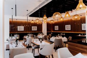 克拉科夫阿斯科特大酒店的餐厅设有白色的桌椅和吊灯。