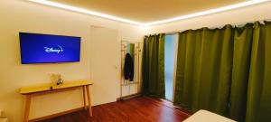 巴黎Jacuzzi LOVE appartement的一间设有绿色窗帘、桌子和电视的客房