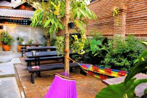 拜县Supermoon Cozy Hostel的花园内种有长椅和树木的吊床