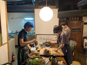 Ayabe一汁一菜の宿　ちゃぶダイニング Ichiju Issai no Yado Chabu Dining Unforgettable Farmstay experience in Deep Kyoto的一群站在厨房准备食物的人
