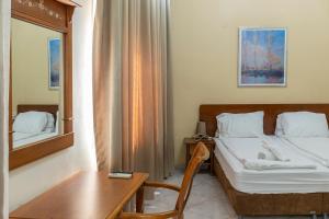 海法港口酒店的一间卧室配有一张床、一张桌子和一面镜子