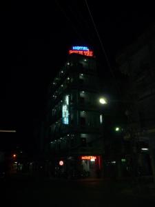 美寿明太酒店的一座高大的建筑,晚上有 ⁇ 虹灯标志