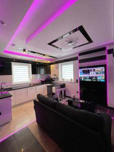 阿斯隆#5 TGHA Luxury One Bedroom Apartment in Athlone的带沙发的客厅和带紫色灯的厨房