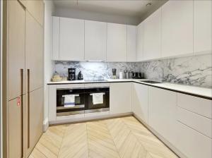 伦敦Luxurious Covent Garden Penthouse的厨房铺有木地板,配有白色橱柜。