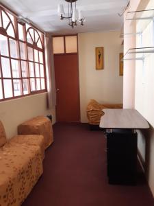 普诺Hostal Vista al Lago Titicaca Puno的客房设有沙发、桌子和窗户。