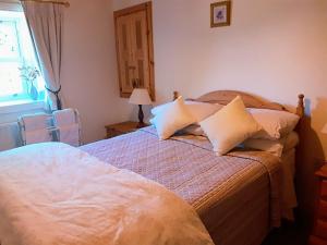 GarrykennedyLackaroe Cottage的卧室配有带枕头的床铺和窗户。