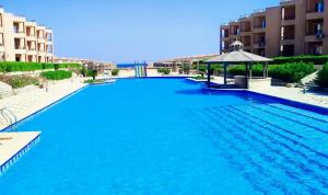 艾因苏赫纳Cozy Chalet in El Ain El Sokhna شالية بالعين السخنة的一个带凉亭的大型蓝色游泳池