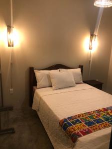 皮廷布Pousada Vila Lua Bela的卧室配有一张床,墙上有两盏灯