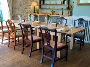汤顿Farthings Country House Hotel & Restaurant Tunton的一张带椅子的木桌和一张带玻璃杯的长桌