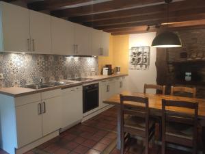 胡法利兹Le Héron的厨房配有白色橱柜和木桌
