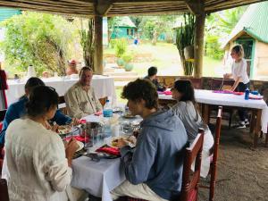 阿鲁沙Songota Falls Lodge的一群坐在餐桌上吃食物的人