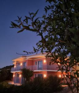 阿尔戈斯托利翁Julietta Suites的大型粉红色房屋,晚上设有阳台