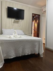 萨尔瓦多Hostel Salvador Orquídeas的卧室配有白色的床,墙上配有电视