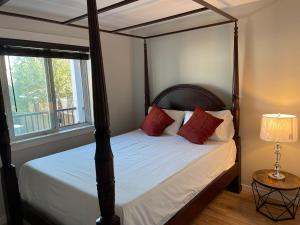 苏克Sooke Vacation suite的一间卧室配有一张带红色枕头的四柱床
