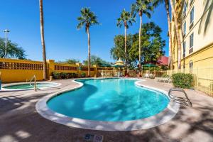 皮奥里亚凤凰城西皮奥里亚拉昆塔套房酒店的一座棕榈树游泳池和一座建筑