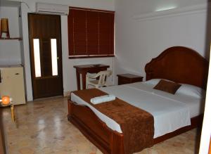 Puerto BerríoHotel Tayrona的一间卧室配有一张床、一张桌子和一个窗户。