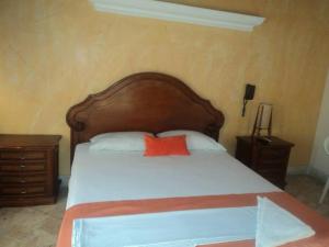 Puerto BerríoHotel Tayrona的一张带木制床头板和红色枕头的床