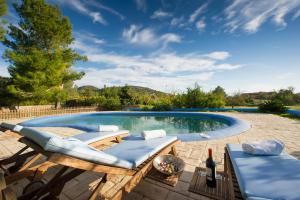伊维萨镇卡尔拉度假屋的一个带2把躺椅和一瓶葡萄酒的游泳池